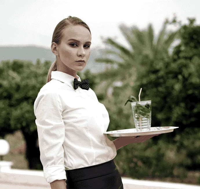 Waitress in a white shirt and bow tie carrying a tray of drinks
